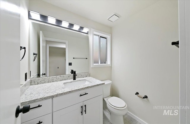 bathroom with toilet, vanity, and baseboards
