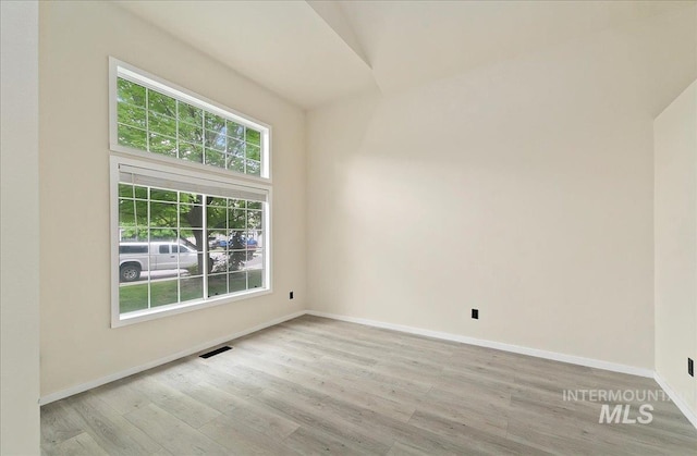 spare room featuring healthy amount of natural light, wood finished floors, and baseboards