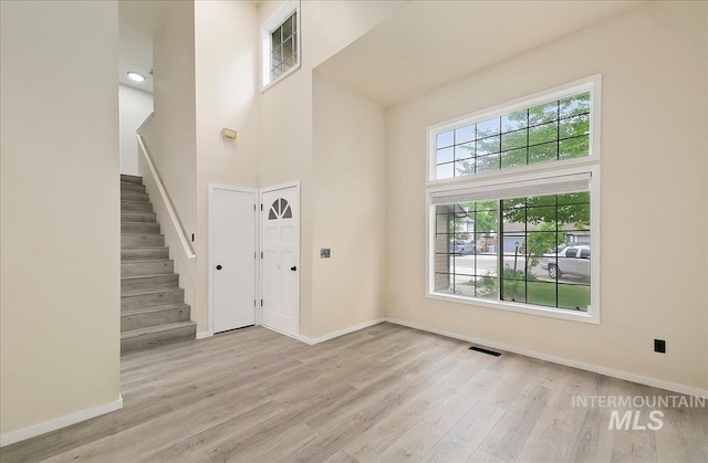 entryway with wood finished floors, a high ceiling, stairway, and baseboards