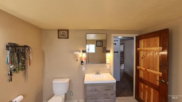 half bath with tile patterned flooring, vanity, and toilet