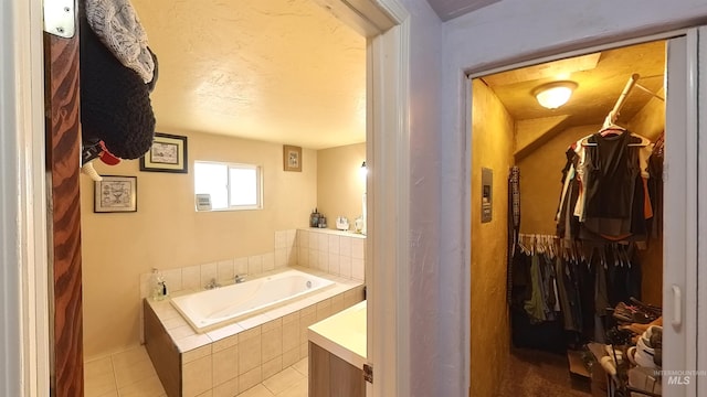 bathroom featuring a garden tub, a walk in closet, and tile patterned floors