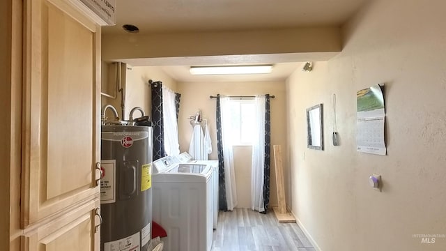 laundry area with electric water heater, light wood-style flooring, and separate washer and dryer