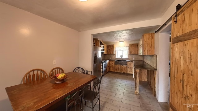 dining area with dark tile patterned flooring and a barn door