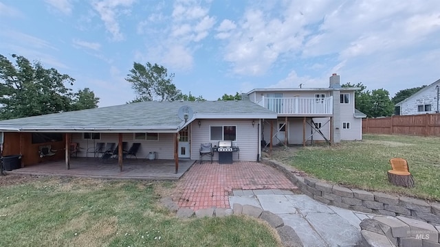 rear view of property with a deck, a yard, a chimney, and fence