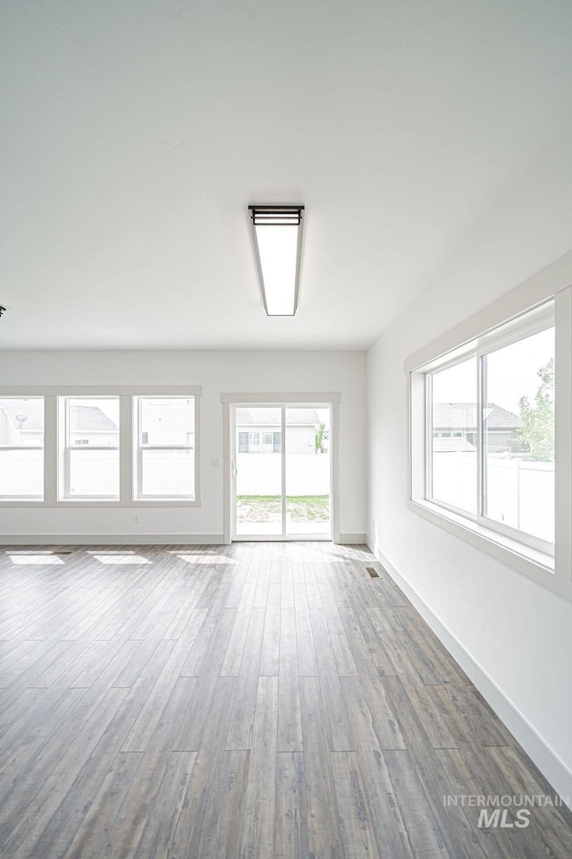 665 Emma Ct, Idaho Falls, ID 83404 - unfurnished living room featuring wood finished floors, plenty of natural light, and baseboards