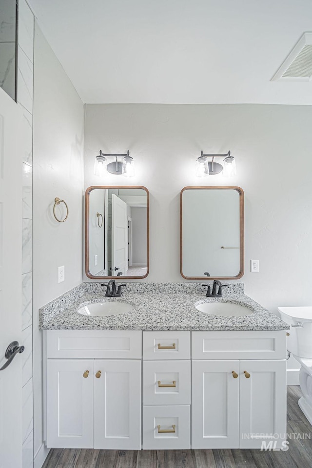 665 Emma Ct, Idaho Falls, ID 83404 - bathroom featuring double vanity, wood finished floors, and toilet