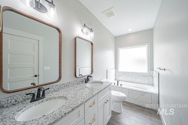 665 Emma Ct, Idaho Falls, ID 83404 - bathroom with wood finished floors, a garden tub, double vanity, and toilet