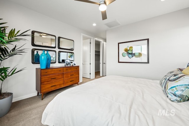 bedroom featuring baseboards, visible vents, a ceiling fan, light colored carpet, and a spacious closet