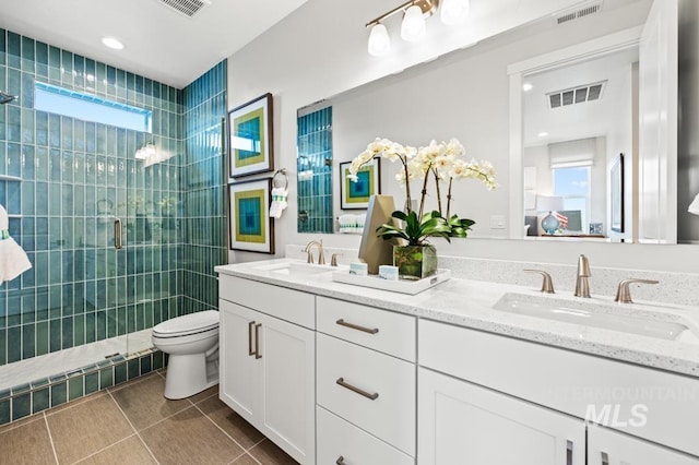 bathroom with a stall shower, visible vents, and a sink