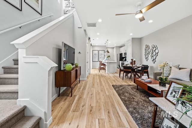 living room with ceiling fan, recessed lighting, visible vents, stairs, and light wood-type flooring