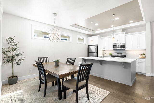 dining room with a raised ceiling, recessed lighting, dark wood-style floors, and a chandelier