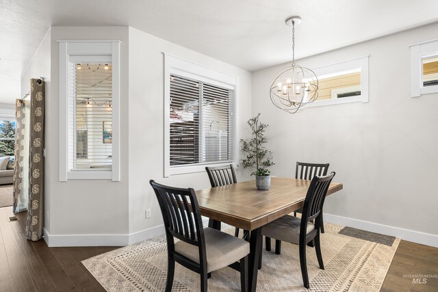 dining area featuring an inviting chandelier, baseboards, and dark wood-type flooring