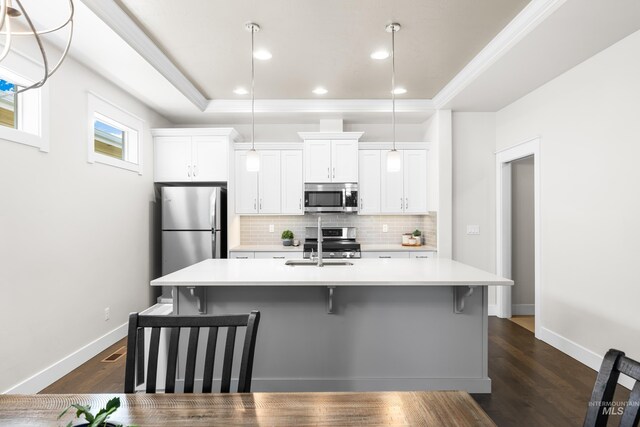 kitchen featuring a breakfast bar, light countertops, stainless steel appliances, decorative backsplash, and a center island with sink