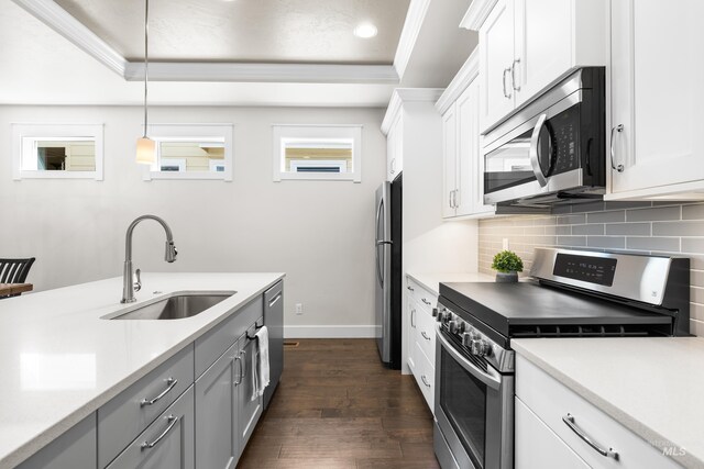 kitchen featuring decorative backsplash, appliances with stainless steel finishes, dark wood finished floors, a sink, and light countertops