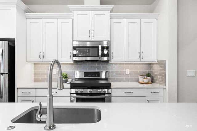 kitchen with a sink, appliances with stainless steel finishes, white cabinets, and light countertops