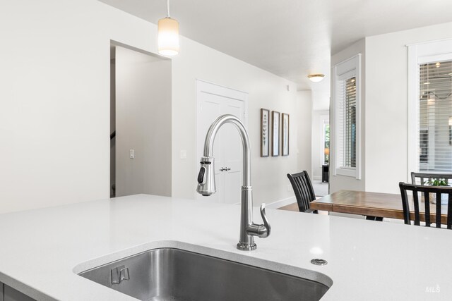 details featuring a sink, light countertops, and pendant lighting