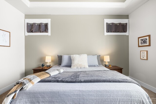 carpeted bedroom featuring baseboards, a raised ceiling, and crown molding