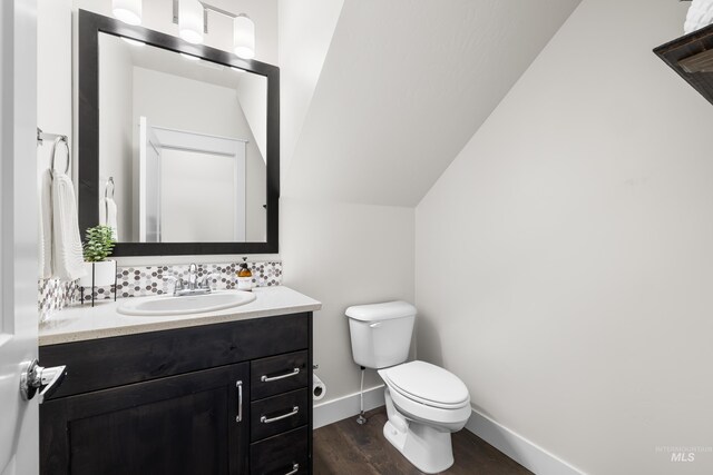 half bath with vanity, baseboards, wood finished floors, and toilet