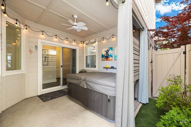 view of patio / terrace with fence, a gate, ceiling fan, and a hot tub