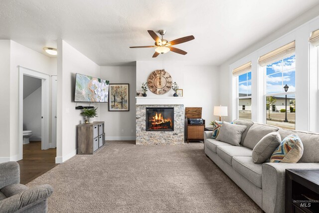 living room featuring baseboards, a ceiling fan, carpet, and a fireplace