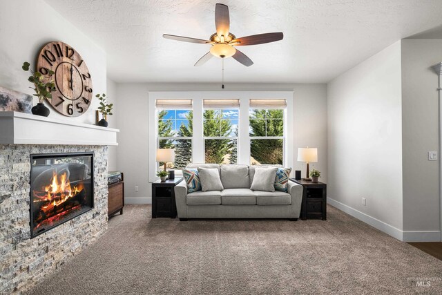 living room with carpet floors, baseboards, ceiling fan, and a fireplace