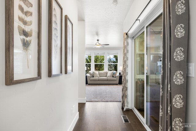 hall with baseboards, dark wood finished floors, and visible vents