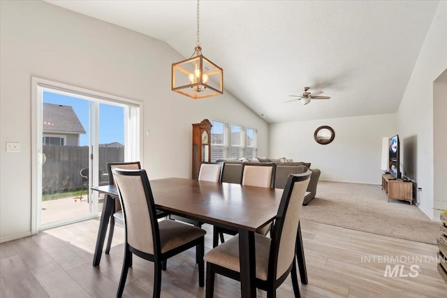 dining room with light wood-style floors, a wealth of natural light, lofted ceiling, and ceiling fan with notable chandelier
