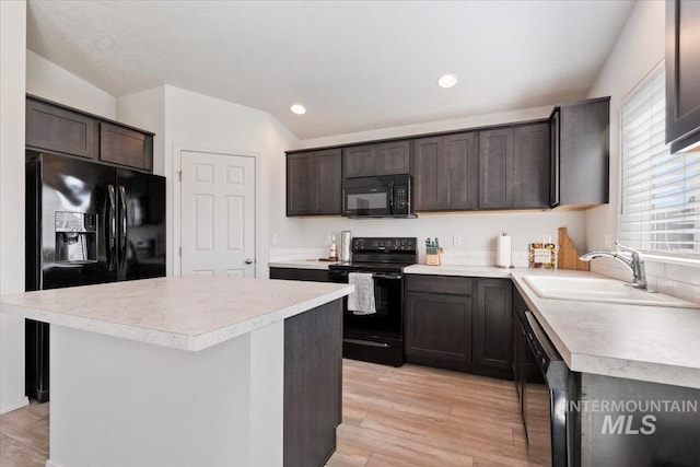 kitchen with a sink, light countertops, dark brown cabinetry, and black appliances