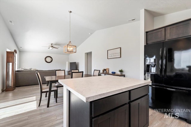 kitchen with light countertops, lofted ceiling, light wood-type flooring, a kitchen island, and black fridge with ice dispenser