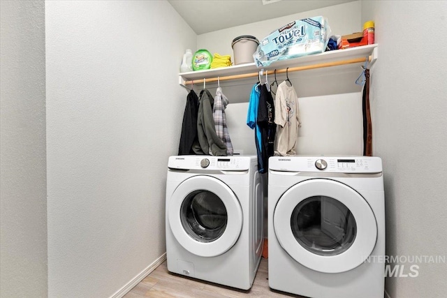 laundry area with washing machine and clothes dryer, laundry area, baseboards, and light wood-type flooring