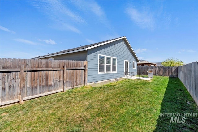 rear view of house with a fenced backyard, a yard, and a patio area