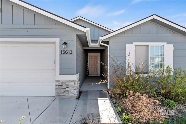 view of front of home featuring board and batten siding, stone siding, and a garage