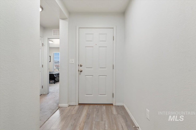 interior space featuring baseboards, visible vents, and light wood-type flooring