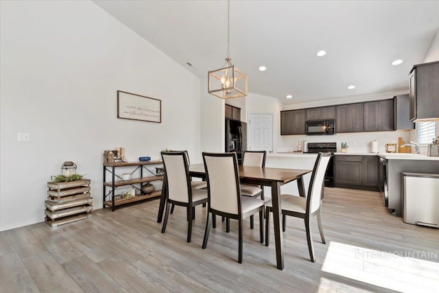 dining area featuring recessed lighting, an inviting chandelier, light wood finished floors, and lofted ceiling