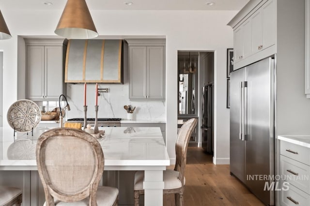 kitchen with ventilation hood, freestanding refrigerator, gray cabinetry, and built in refrigerator