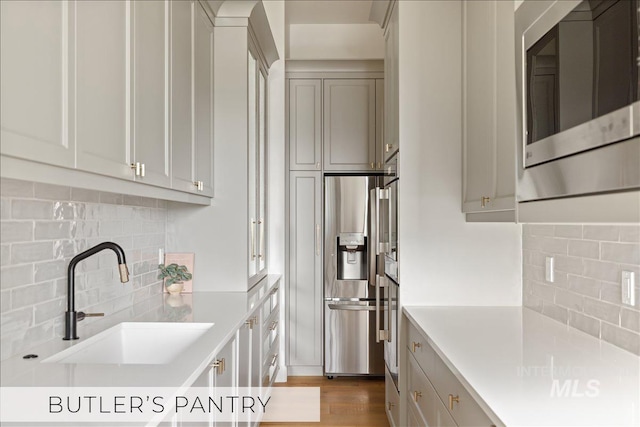 kitchen with wood finished floors, light countertops, appliances with stainless steel finishes, and a sink