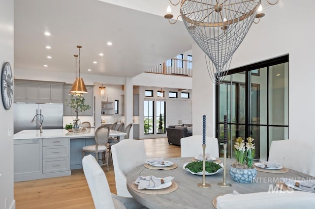 dining room with light wood-style floors, a high ceiling, a notable chandelier, and recessed lighting