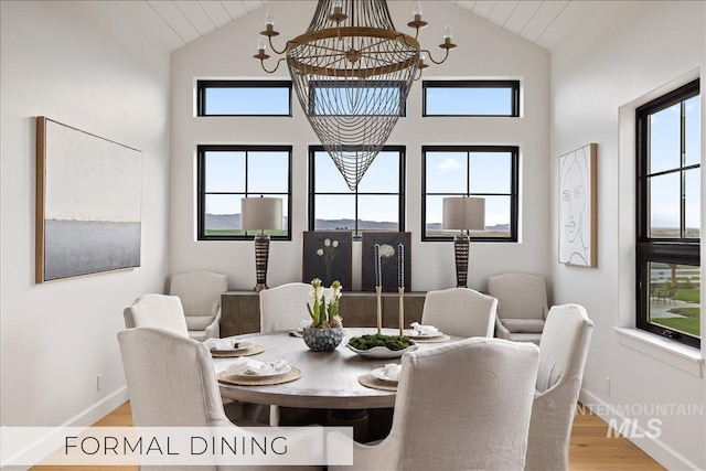 dining room with a chandelier, lofted ceiling, baseboards, and light wood finished floors