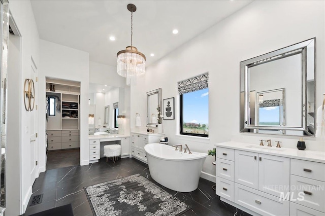 bathroom featuring recessed lighting, a soaking tub, two vanities, a sink, and a chandelier