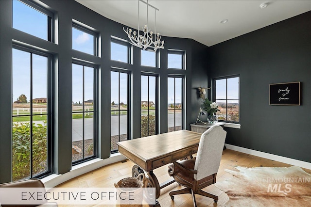 dining space with light wood finished floors, plenty of natural light, baseboards, and a notable chandelier