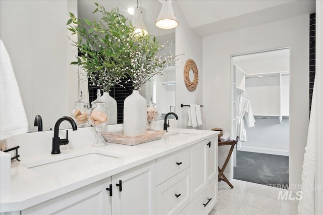 bathroom featuring double vanity, a sink, and baseboards