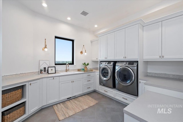 washroom with cabinet space, visible vents, washing machine and clothes dryer, a sink, and recessed lighting