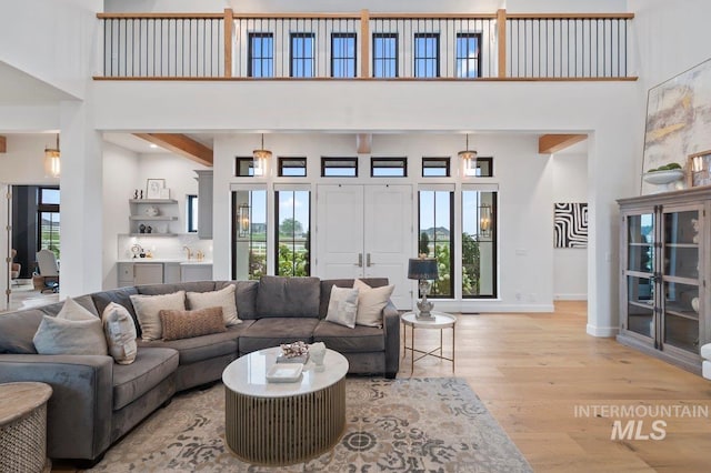 living room featuring light wood finished floors, a high ceiling, and baseboards