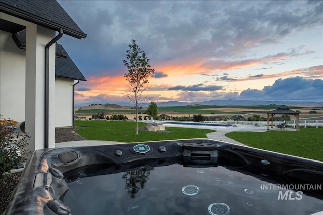 exterior space with a rural view, a mountain view, a hot tub, and a gazebo