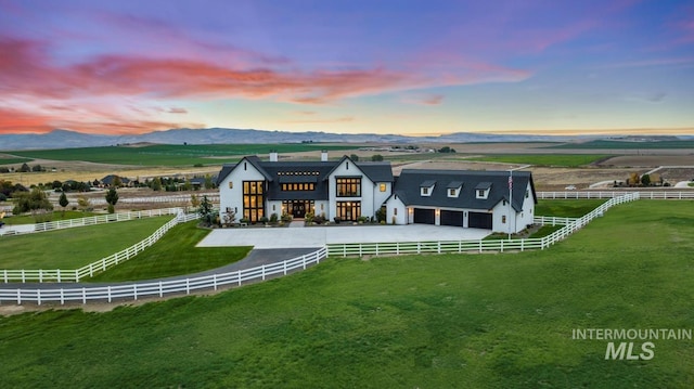 back of property with a yard, fence, a mountain view, a rural view, and driveway