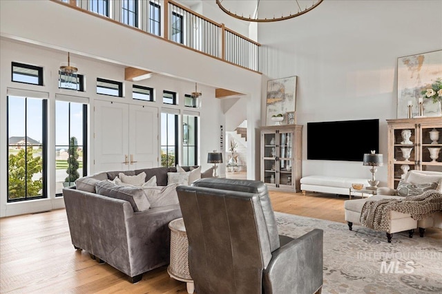 living area featuring light wood-type flooring, a healthy amount of sunlight, and a high ceiling