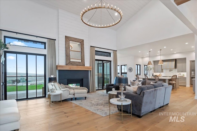 living room with plenty of natural light, a fireplace, a notable chandelier, and light wood-style flooring