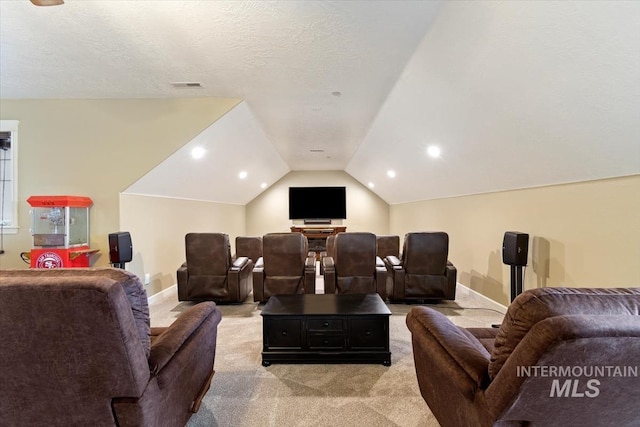 cinema featuring light carpet, vaulted ceiling, and a textured ceiling