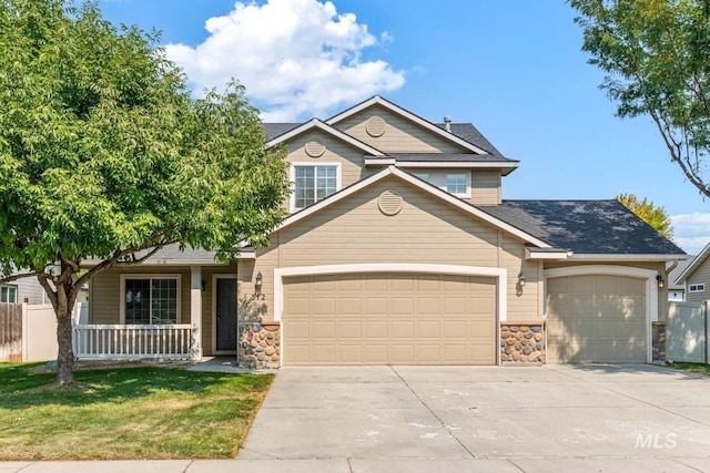 view of front of home featuring covered porch, a garage, and a front lawn