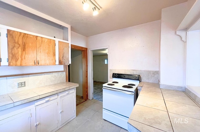 kitchen with white electric stove, tile countertops, decorative backsplash, and light tile patterned floors